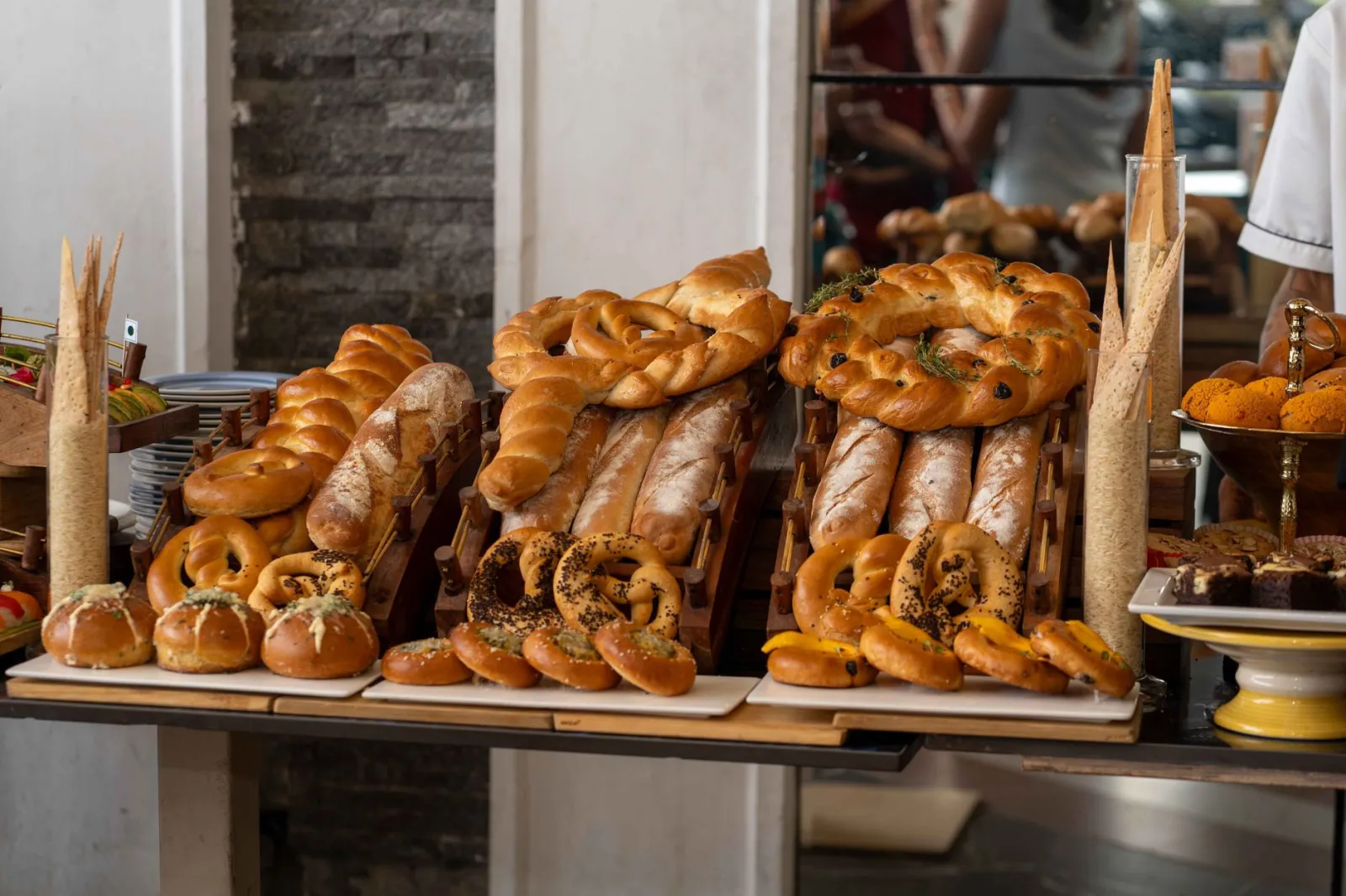 A variety of freshly baked breads and pastries elegantly displayed indoors on a wooden table.